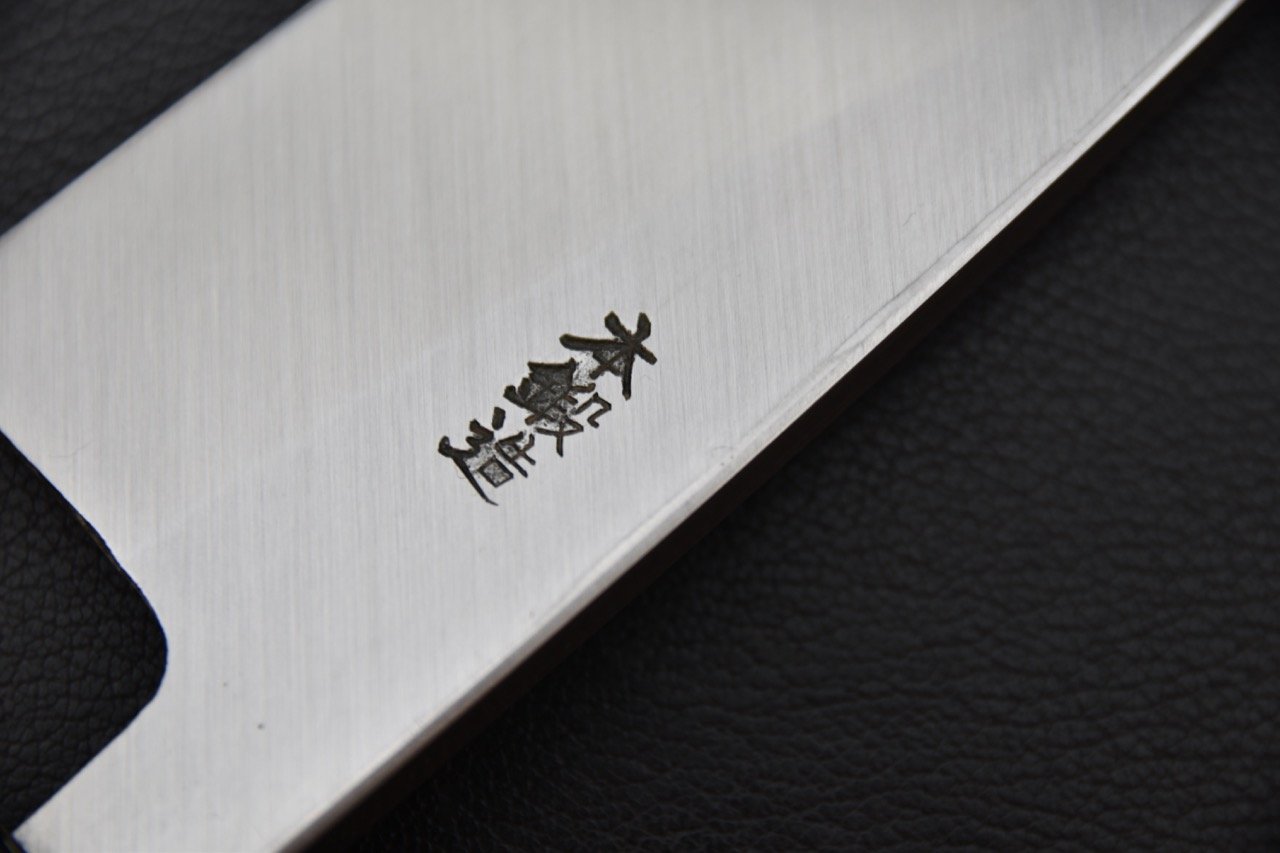 Gros plan sur la lame d'un couteau japonais avec des inscriptions gravées dessus