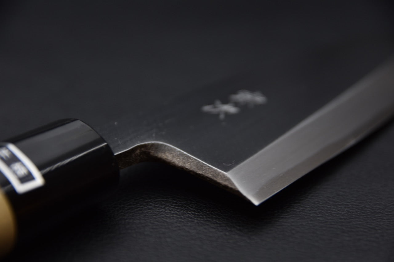 Gros plan sur la lame d'un couteau japonais Ai deba avec manche en bois