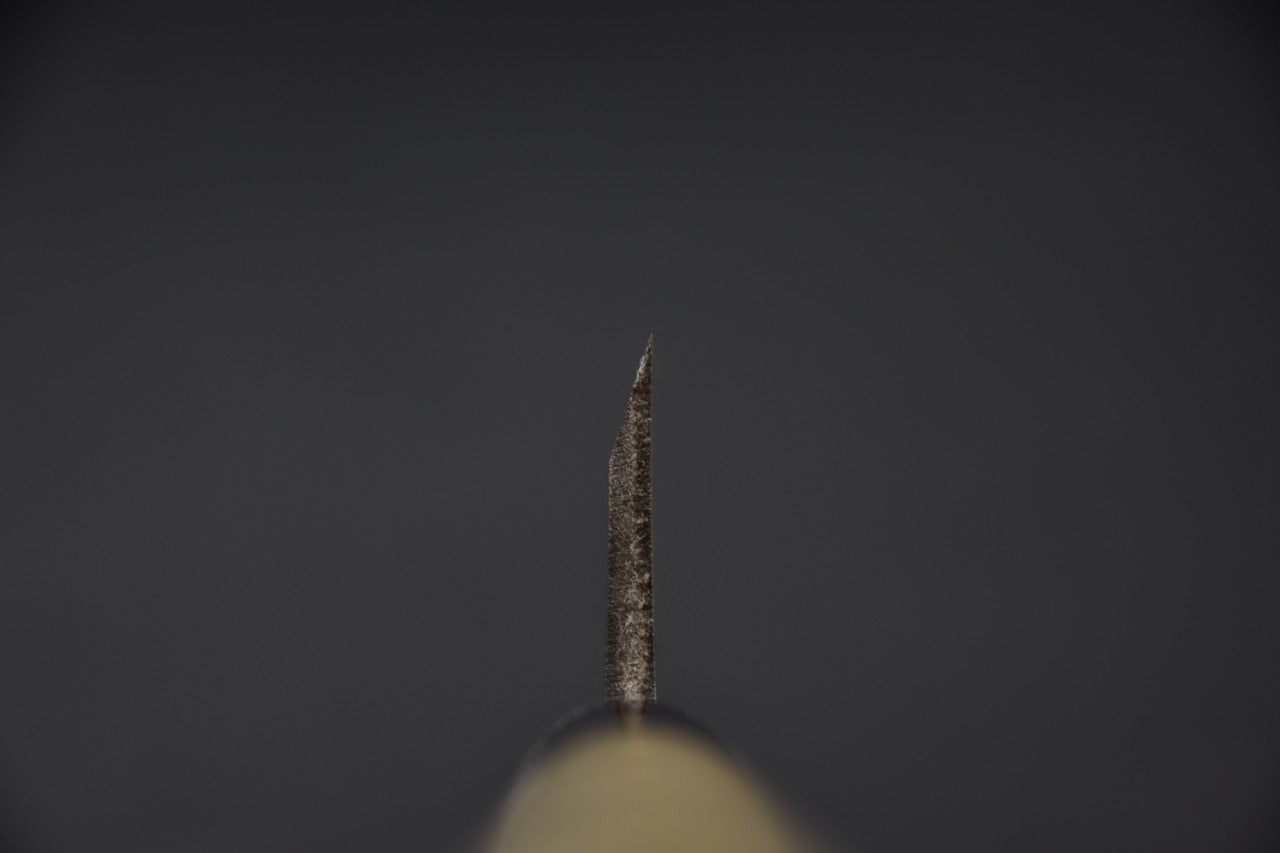 Gros plan sur le talon d'un couteau japonais Ai deba avec fond sombre