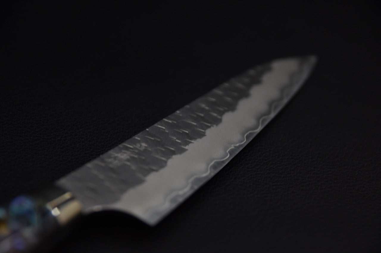 Lame de couteau japonais damassé vue de près avec manche nacré sur fond noir