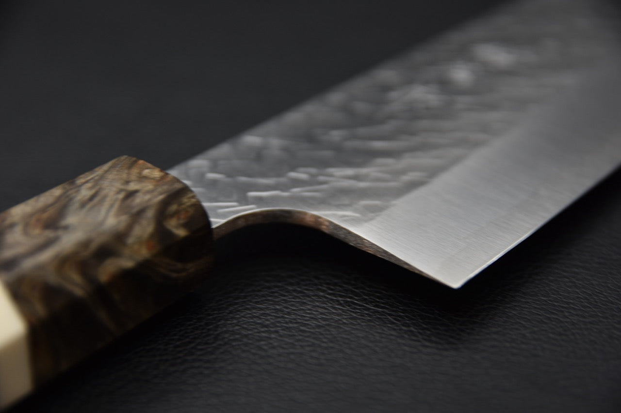 Vue rapprochée du ricasso et de la transition entre la lame et le manche du couteau japonais Santoku.