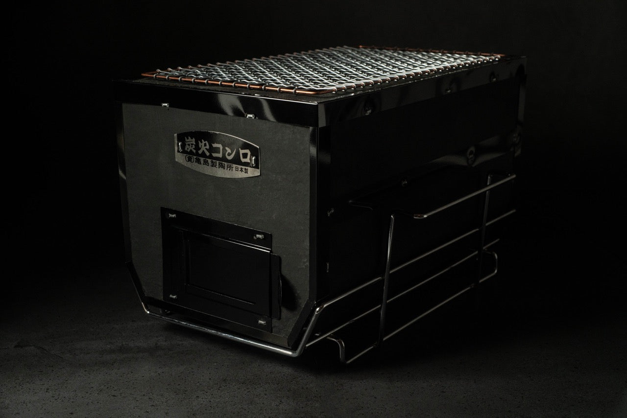 Black rectangular Sumibi Yakitori Konro grill with mesh grate and metal stand, designed for charcoal grilling, on a dark background.