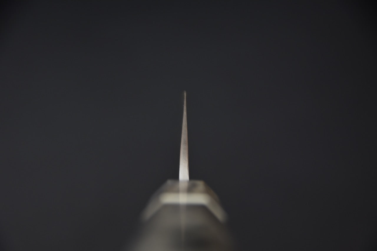 Vue frontale de l’émouture fine et du fil acéré d’un couteau japonais Sujihiki Yoshikane.