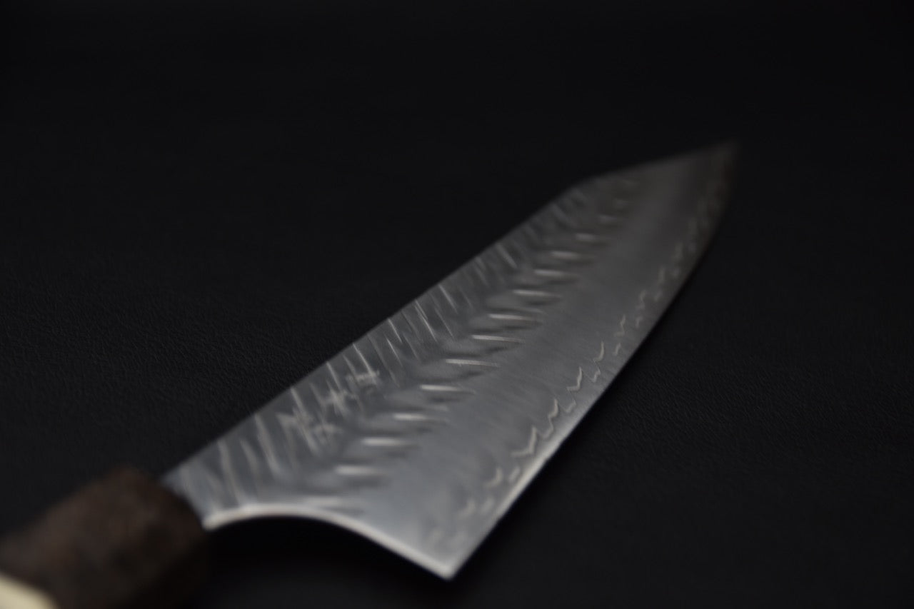 Détail de la lame d’un couteau japonais Kiritsuke avec finition brillante et gravure.
