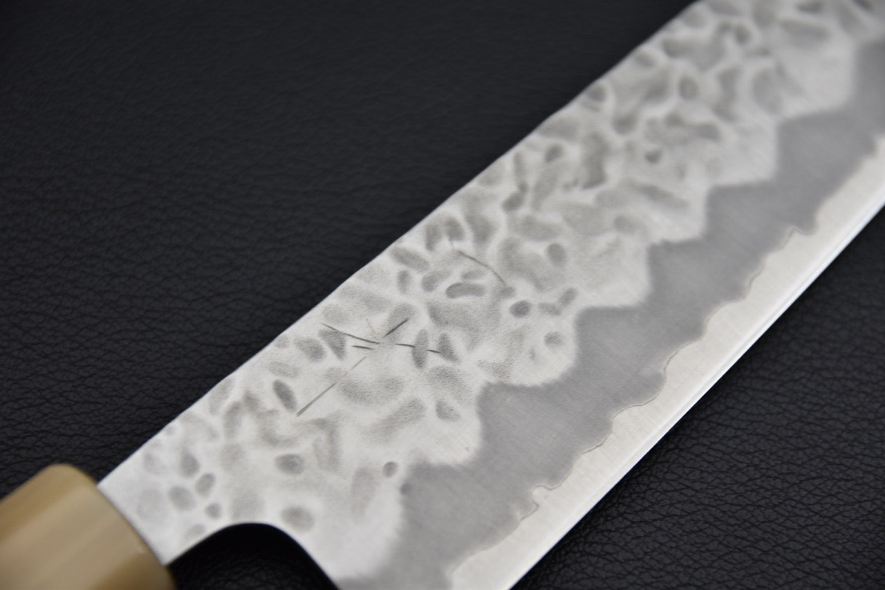 Couteau japonais bunka, gros plan sur la finition tsuchime et la ligne hagane ondulée près du tranchant
