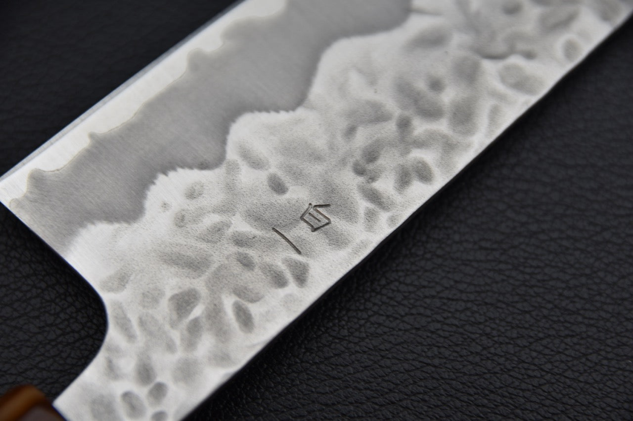 Couteau japonais bunka, gros plan sur les kanji gravés sur la lame et la finition martelée