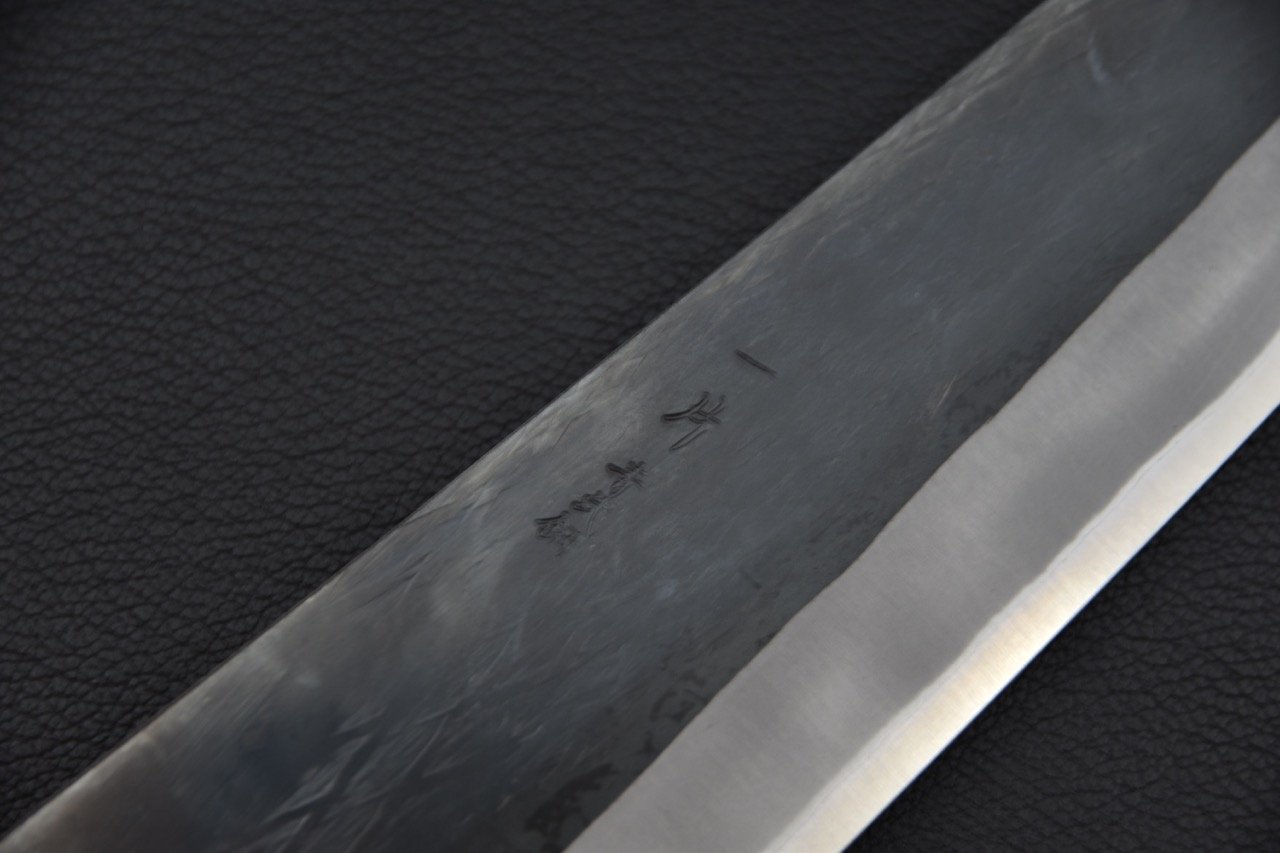 Gros plan sur la lame en acier Aogami 2 du couteau japonais Gyuto avec finition kurouchi