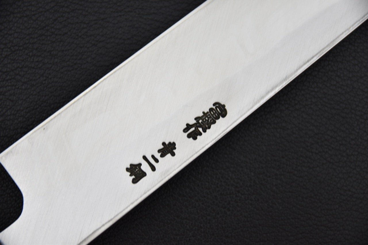 Gros plan sur la lame d'un couteau Yanagiba avec des inscriptions japonaises gravées