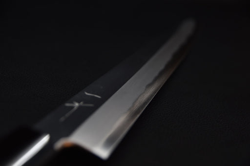 Gros plan sur la pointe d'un couteau japonais Kiritsuke yanagiba sur fond sombre