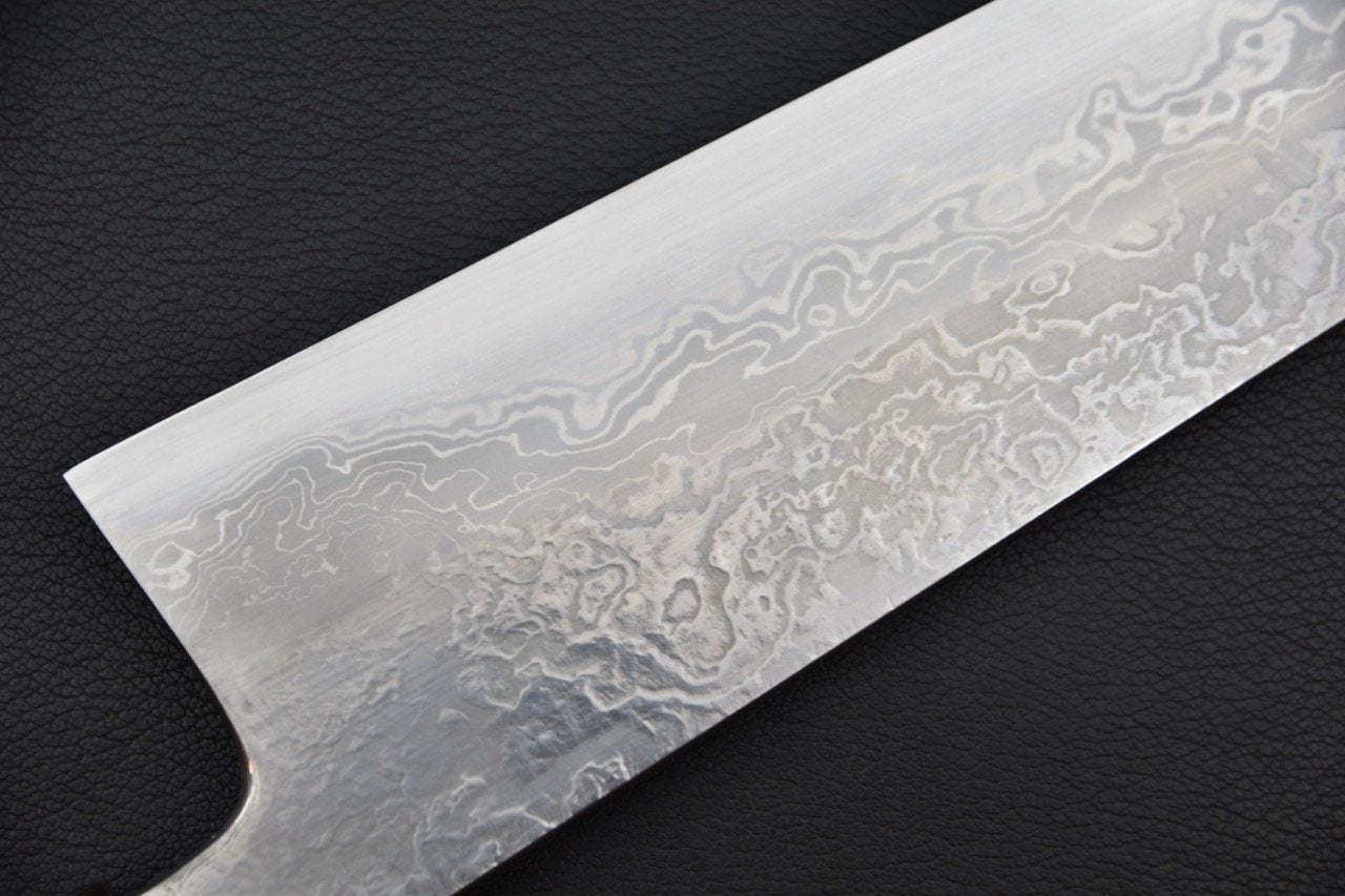 Gros plan sur la lame damassée d'un couteau Gyuto japonais en acier Aogami 1