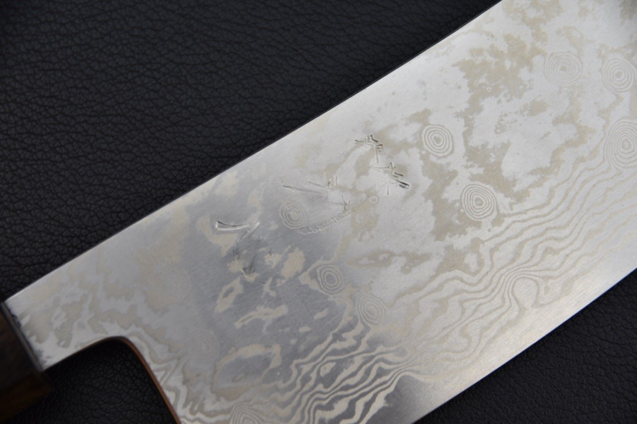 Gros plan sur la lame en acier Damascus du couteau japonais Tsubaki avec motifs élégants