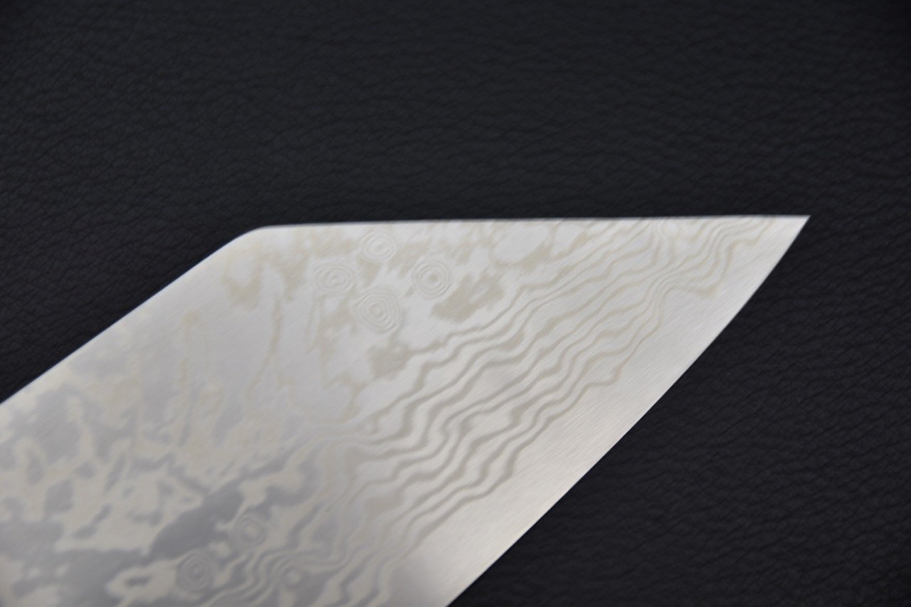 Gros plan sur la pointe de la lame en acier Damascus du couteau japonais Tsubaki avec motifs uniques