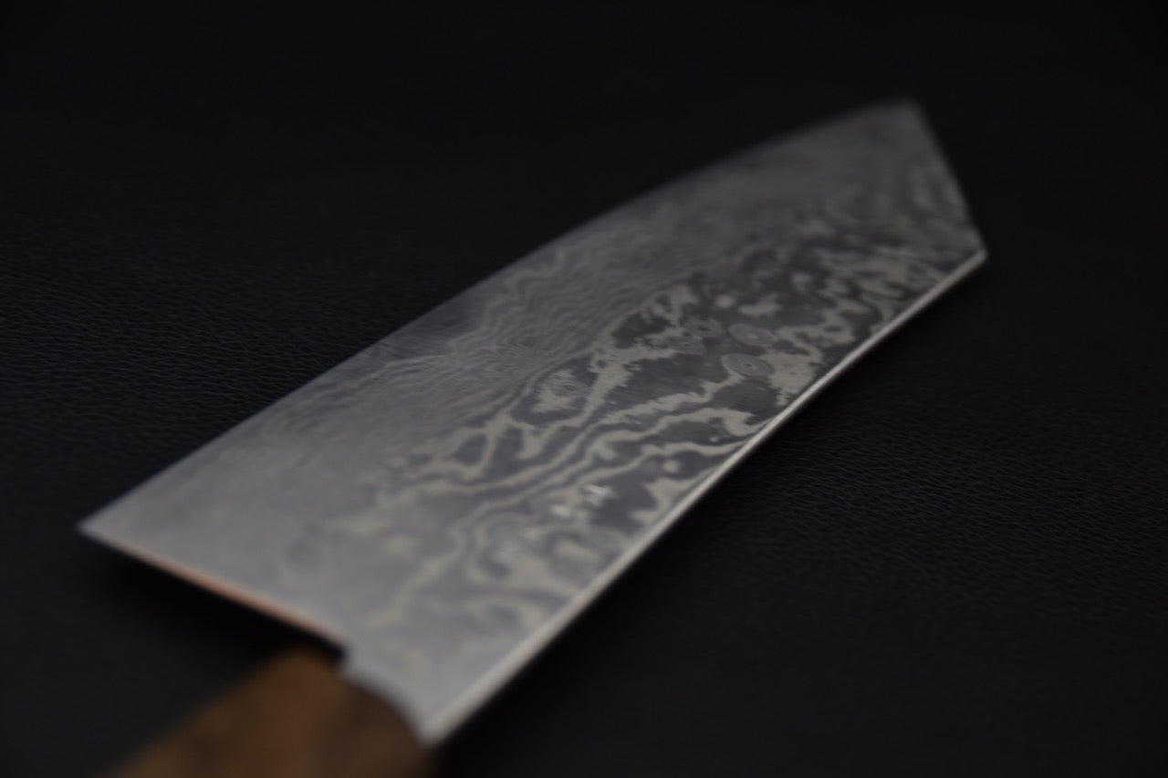 Gros plan sur la lame en acier Damascus du couteau japonais Tsubaki avec motif distinctif