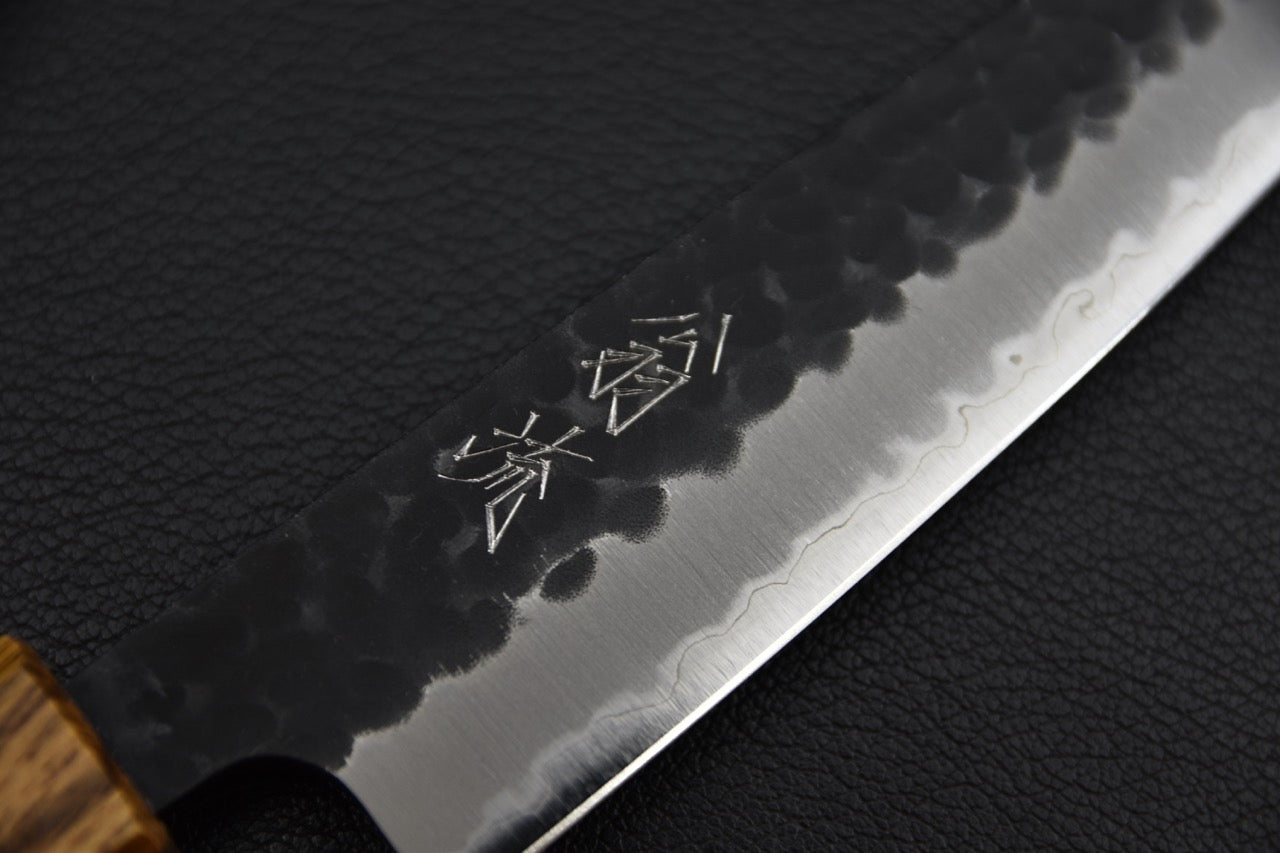 Couteau japonais petty 135 mm — détail du plat de lame côté gauche, kanji gravés et ligne hagane ondulée