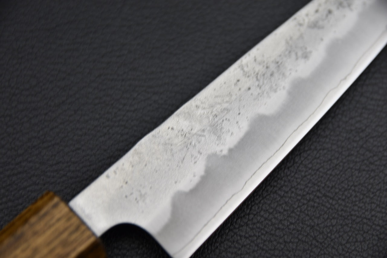 Couteau japonais 135 mm, gros plan sur la zone kasumi de la lame révélant la texture de forge artisanale et la ligne hagane — Stay Sharp Montréal.