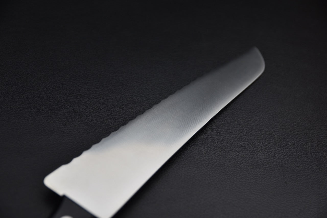 Couteau à pain — gros plan sur la pointe de la lame, tranchant cranté