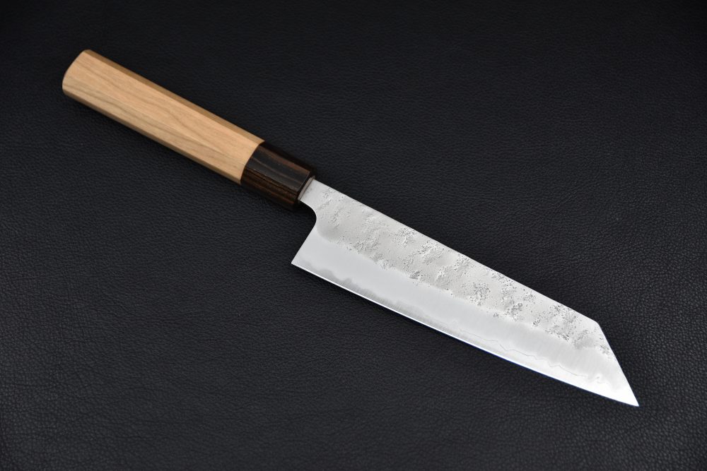Couteau japonais Kiritsuke avec lame martelée et manche en bois clair sur fond noir