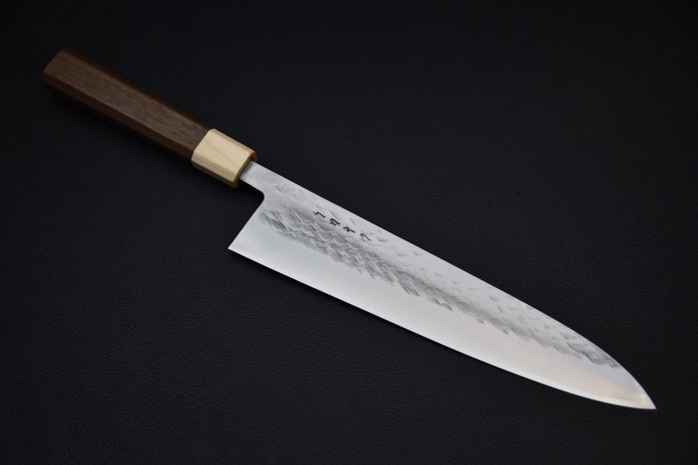 Couteau de chef japonais avec lame martelée et manche en bois sur fond noir