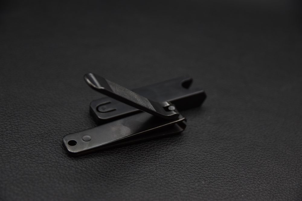 Set of small black metal folding clips arranged on a dark textured background.
