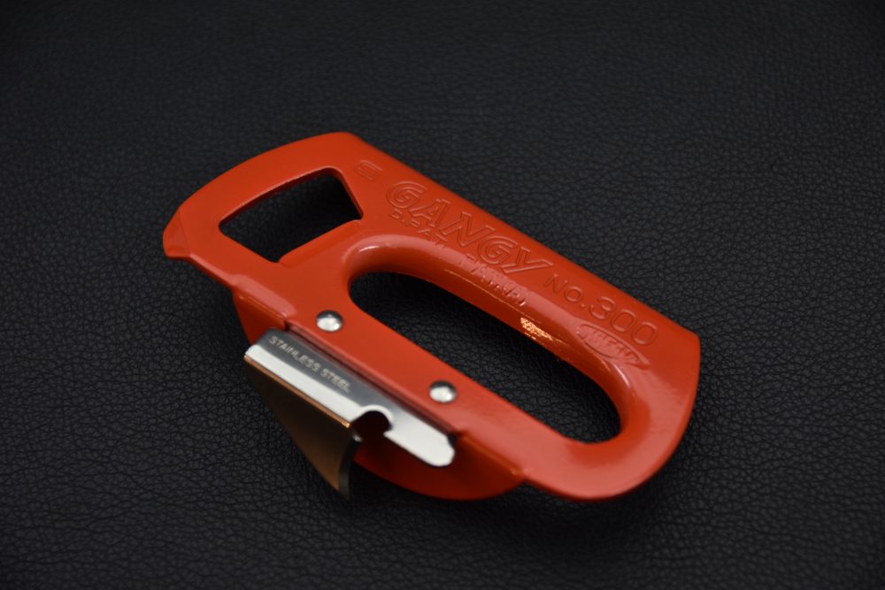 Red Japanese shellfish cutter featuring a stainless-steel blade, displayed on a dark textured background.