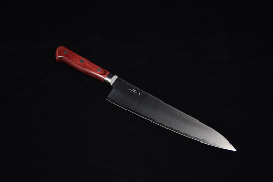 Japanese chef knife with a long stainless steel blade and a red wooden handle featuring three rivets, placed on a black background.