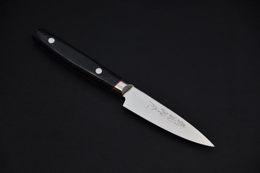 Japanese paring knife with a polished blade and black micarta handle featuring two rivets, displayed on a dark background.