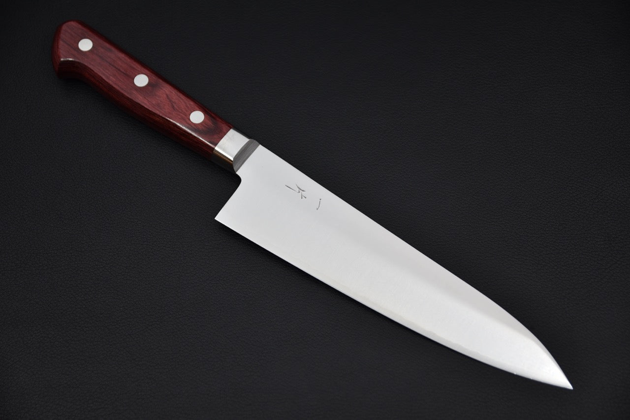 Japanese chef knife with a polished stainless steel blade and a red wooden handle featuring three rivets, placed on a black background.
