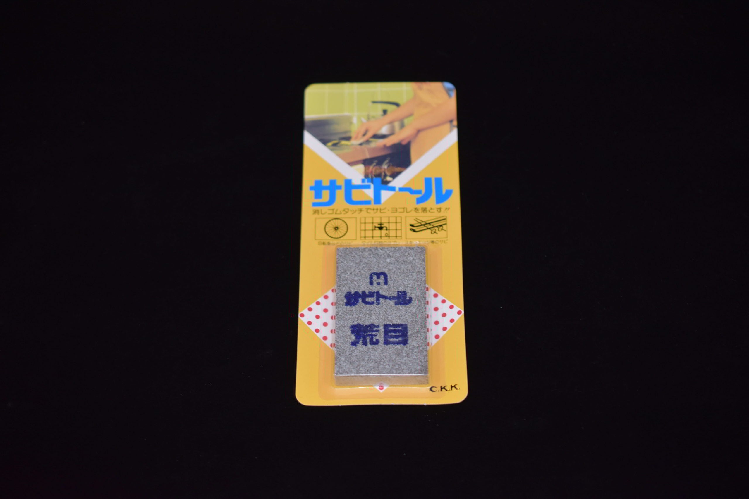 Japanese rust-eraser block in yellow packaging with blue text and product images, displayed against a dark background.