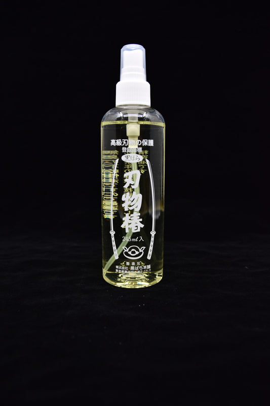 Bottle of Japanese blade oil with a spray nozzle, labeled in Japanese, standing upright against a black background.