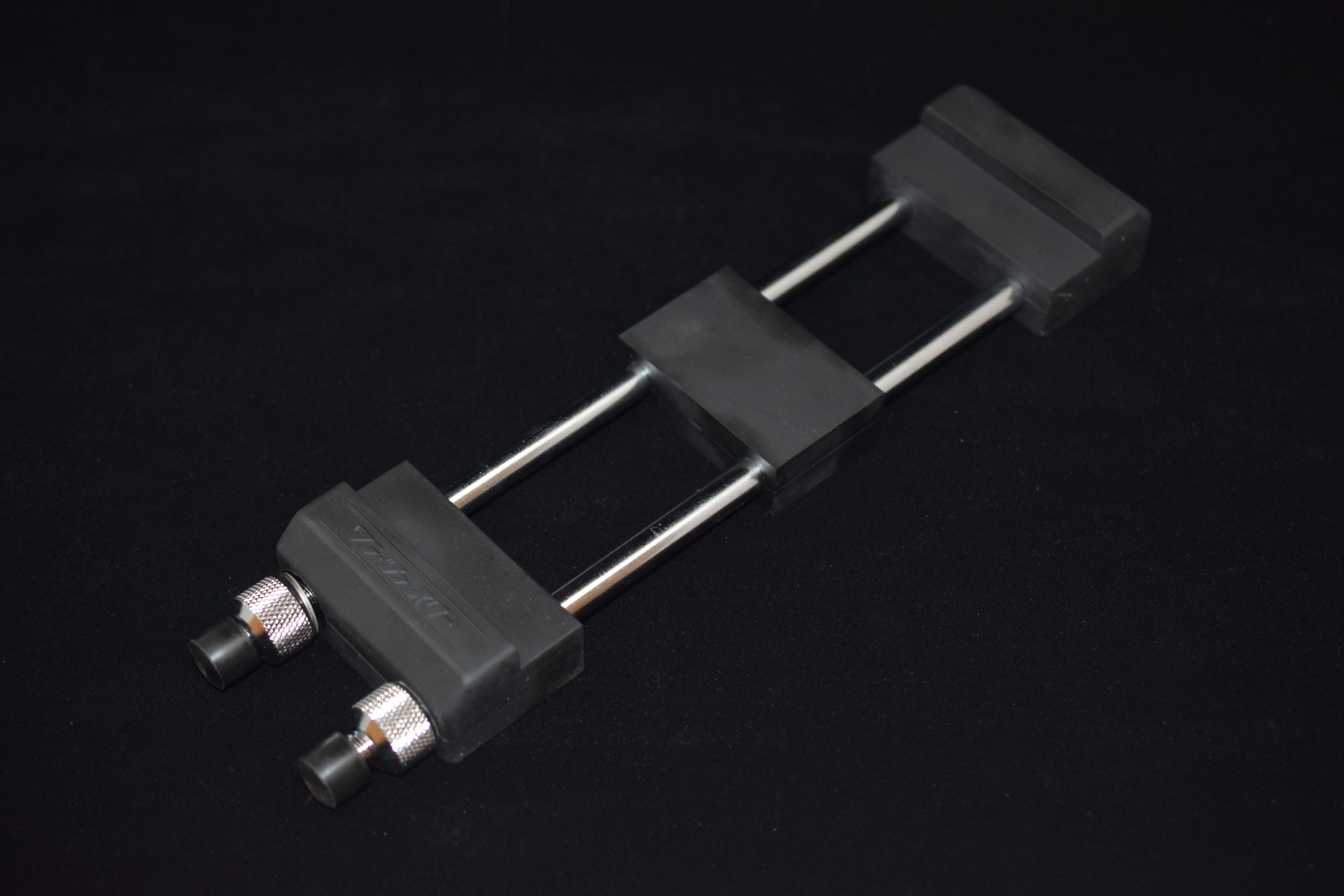 Sharpening guide with two metal rods and adjustable rubber-tipped clamps, designed to hold a blade at a steady angle during sharpening.